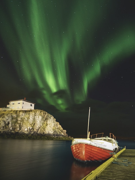 Aurora boreal encima de un barco en el muelle en Islandia