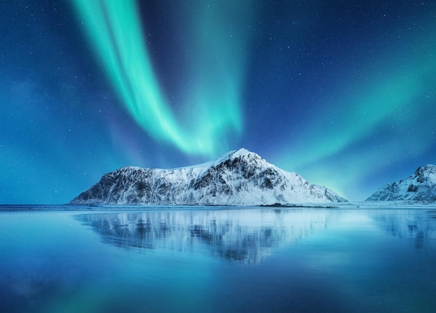 Aurora Boreal Islas Lofoten Noruega Luces del norte montañas y reflejo en el agua Paisaje invernal durante las luces polares Noruega imagen de viaje