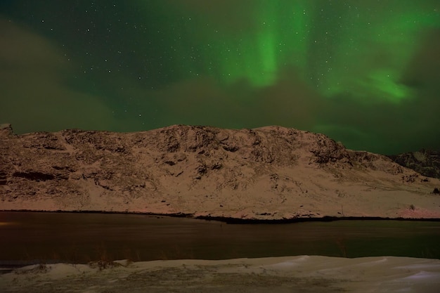 Aurora boreal Luzes verdes do norte acima das montanhas nas ilhas Lofoten, Noruega. Céu noturno com luzes polares. Paisagem noturna de inverno com aurora.