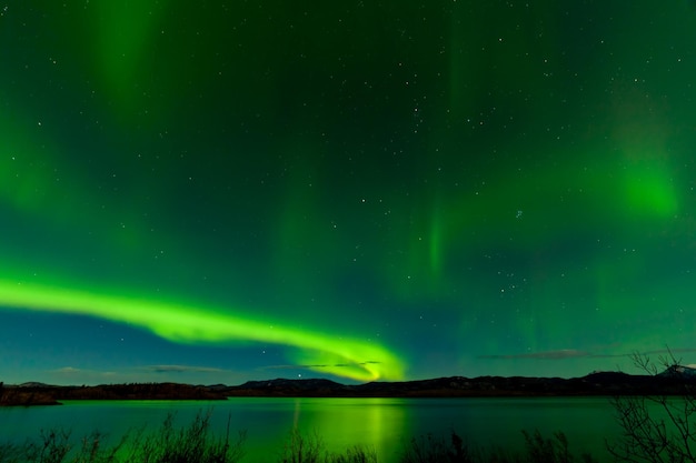 Aurora boreal muestra la superficie del lago Laberge reflejada