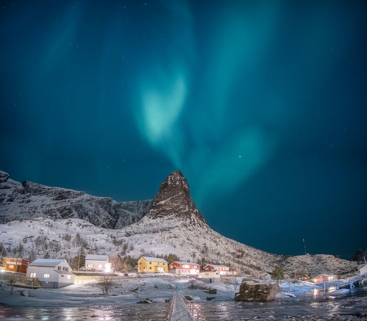 Foto aurora boreal na montanha de neve com vila de pescadores nas ilhas lofoten