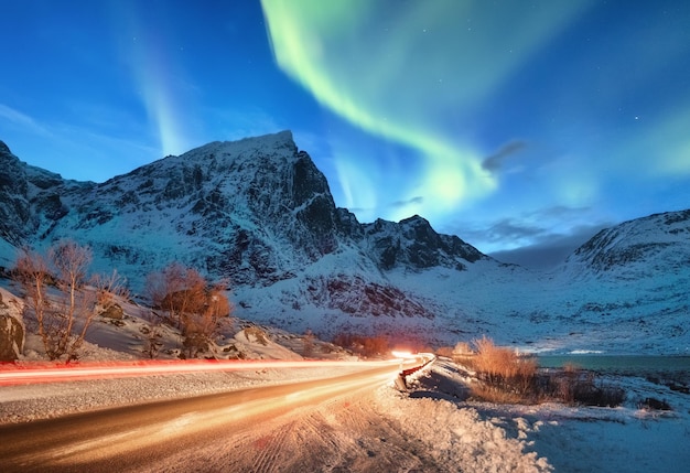 Aurora Borealis auf den Lofoten-Inseln Norwegen Straßenverkehr und Unschärfe Autolicht Grüne Nordlichter über Bergen Nachthimmel mit Polarlichtern Natürlicher Hintergrund in Norwegen