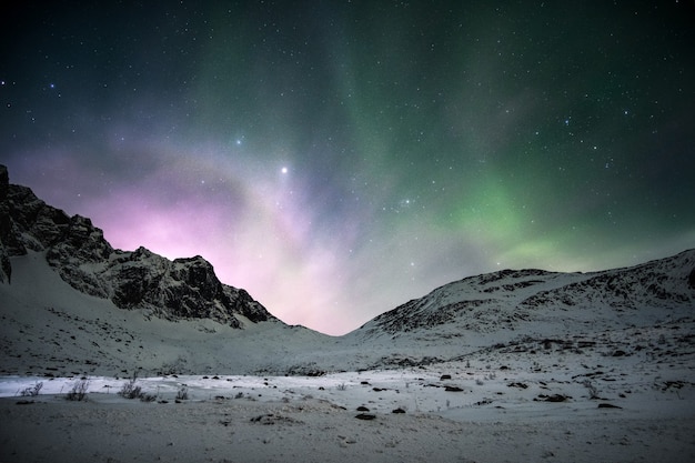 Aurora borealis mit Sonnenaufgang über der Bergkette am Nachthimmel im Winter