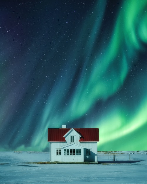 Aurora Borealis über weißem Haus auf Schnee im Winter bei Skandinavien