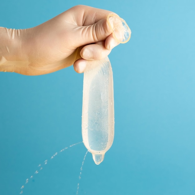Aus einem Kondom voller Löcher tritt Wasser aus Kontrolltest für die Qualität