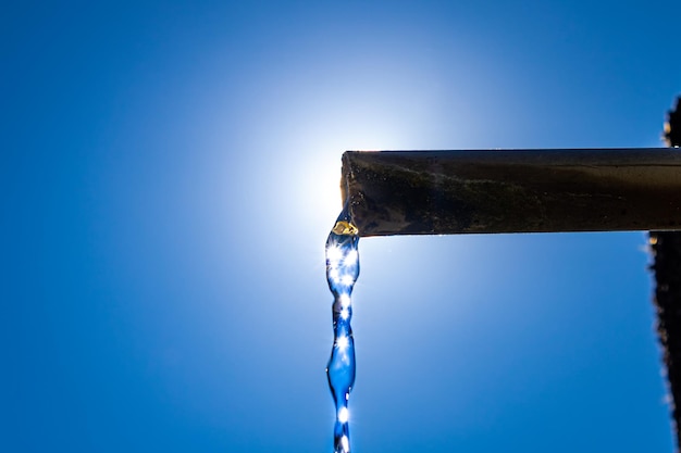 Foto aus einer bergwasserleitung strömendes wasser. gegen sonnenlicht aufgenommenes foto mit detail der auf das wasser scheinenden sonne