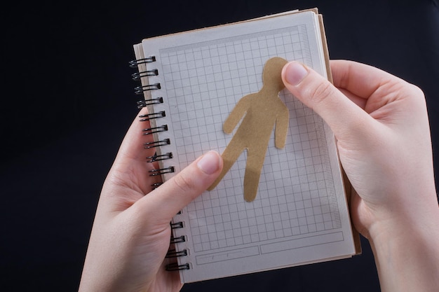 Aus Papier ausgeschnittene Männerform in Notizblock in der Hand