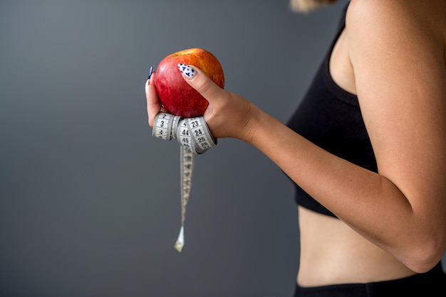 Ausbilderin im Sportanzug mit Apfelmaßband isoliert auf grauem Hintergrund