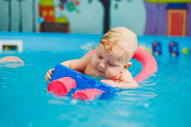 Ausbildung eines Neugeborenen in einem Schwimmbad Ein Schwimmbad für Babys Kindesentwicklung Ein kleines Kind lernt im Schwimmbad schwimmen