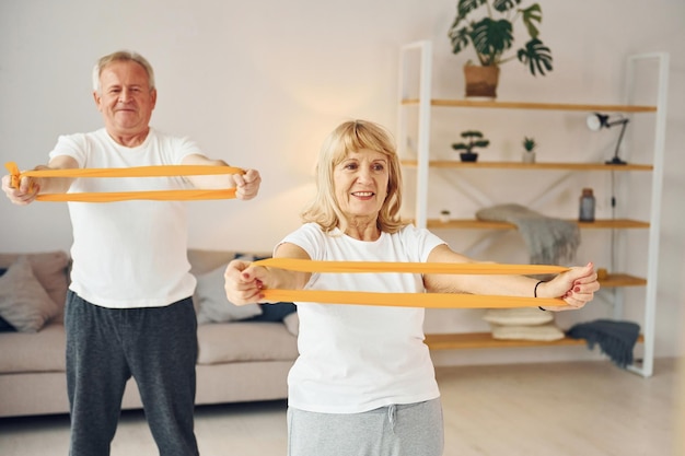 Ausdehnungs- und Fitnessübungen machen ältere Mann und Frau sind zu Hause zusammen
