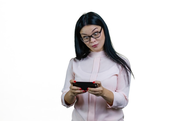 Ausdrucksstarke junge asiatische Frau spielt Videospiel mit weit geöffneten Augen, isoliert auf weißem Hintergrund