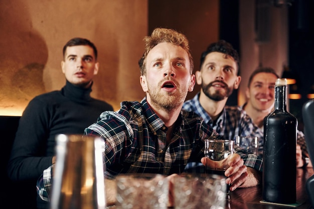 Ausdrucksstarke Menschen, die Fußball gucken Eine Gruppe von Menschen, die drinnen in der Kneipe zusammen sind, haben am Wochenende Spaß