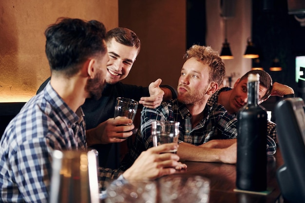 Ausdrucksstarke Menschen, die Fußball gucken Eine Gruppe von Menschen, die drinnen in der Kneipe zusammen sind, haben am Wochenende Spaß