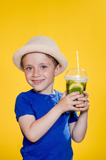 Ausdrucksstarker Junge posiert mit einem Glas Getränk