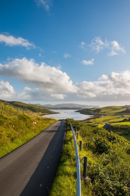 Ausflug oder Abenteuer Verlassene idyllische Straße in Schottland Isle of Skye Bewölkter blauer Himmel