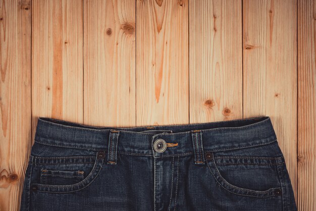 Ausgefranste Jeans oder Blue Jeans-Denimsammlung auf rauem Holztischhintergrund mit Kopienraum, altes Modekonzept.