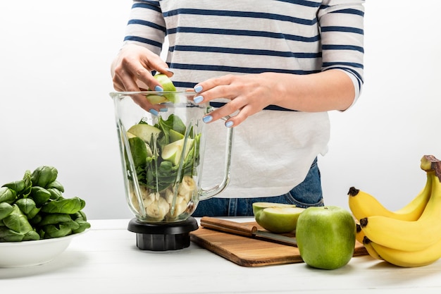 Ausgeschnittene Ansicht einer Frau, die Bio-Früchte in einen Mixer gibt, auf Weiß