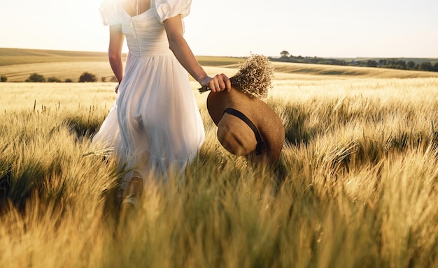 Ausgeschnittene Ansicht Hut in der Hand halten Schöne junge Braut in weißem Kleid ist an sonnigen Tagen auf dem landwirtschaftlichen Feld