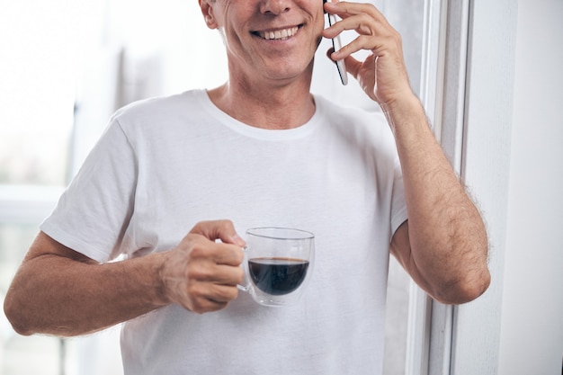 Ausgeschnittenes Foto eines erwachsenen Mannes mit einem glücklichen Lächeln, der eine Tasse Kaffee hält