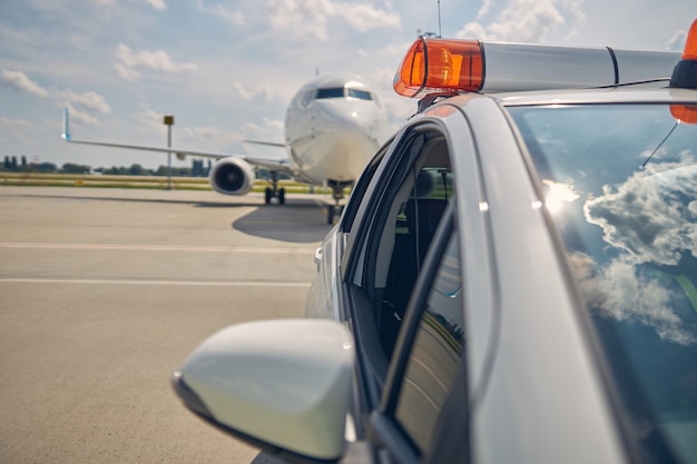 Ausgeschnittenes Foto eines Follow-me-Autos, das das neu angekommene Flugzeug zum Parkplatz leitet