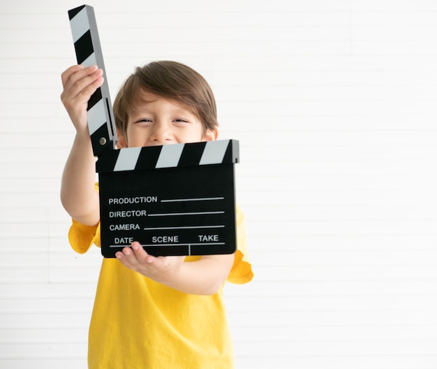 Foto ausgewählter fokusfilm, der klöppelbrett hält, das durch glücklichen jungen hält