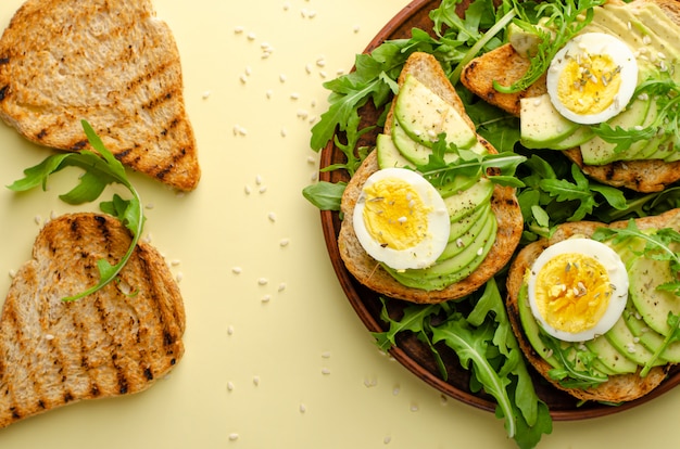 Ausgewogene Ernährung. Avocado Toast mit Ei und Rucola Salat. Über uns flach liegen