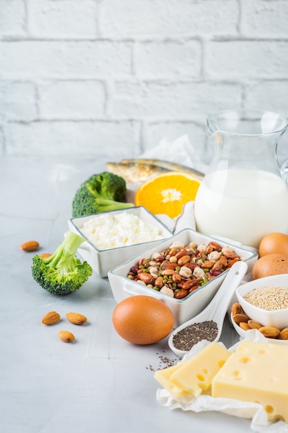 Ausgewogene Ernährung, gesundes Ernährungskonzept. Auswahl an kalziumreichen Nahrungsquellen, Bohnen, Milchprodukten, Sardinen, Brokkoli, Chiasamen, Mandeln auf einem Küchentisch. Raumhintergrund kopieren