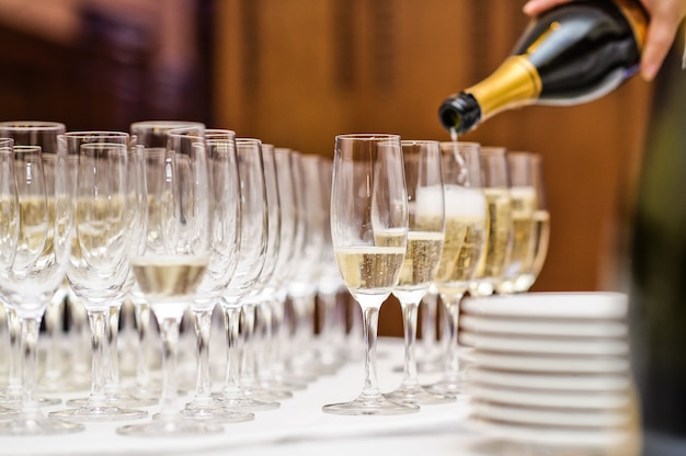 Auslaufender Champagner des Kellners in das Weinglas im Restaurant.