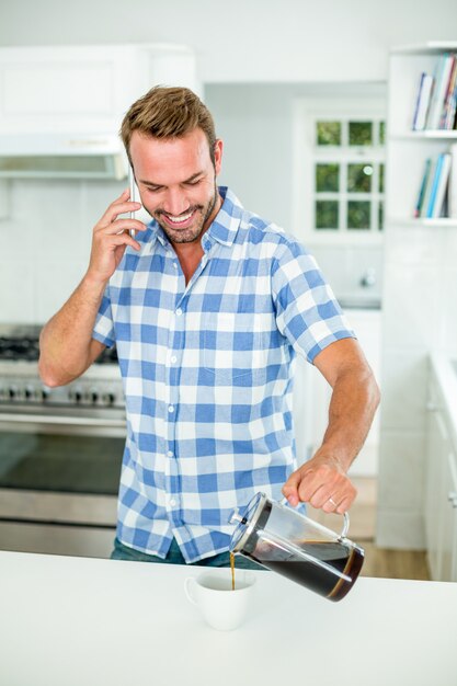 Auslaufender Kaffee des Mannes bei der Unterhaltung auf Mobiltelefon