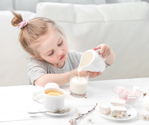 Auslaufendes Milch des kleinen Mädchens in ihre Teetasse