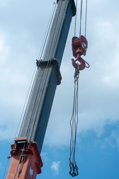 Ausleger eines Turmdrehkrans in Nahaufnahme gegen den blauen Himmel Ein Arbeitskran auf einer Baustelle Blick auf die Kranhakenkabel und andere hydraulische Komponenten und Geräte von Baumaschinen