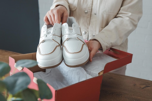 Auspacken von Damenschuhen stilvolle weiße Turnschuhe in den Händen