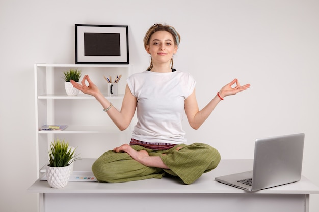 Ausruhen im Amt. Yoga bei der Arbeit. Auf dem Laptop tippen und Lotuspose machen.