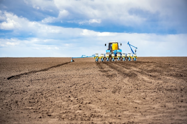 Foto aussaat im feld im frühjahr. traktor mit sämaschine.