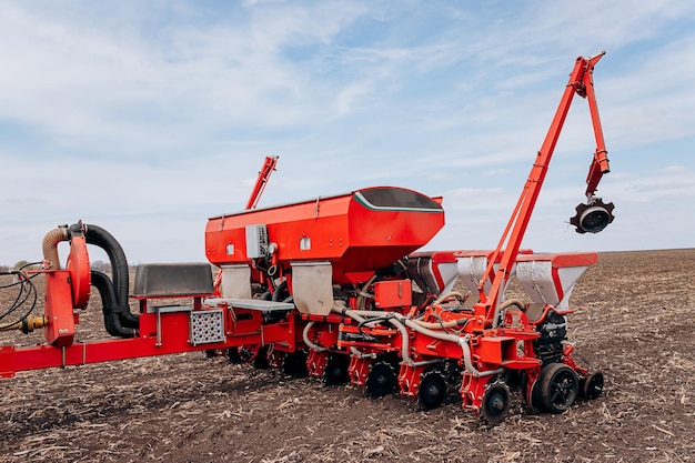 Aussaatsaison im Frühjahr Bauer mit einem Traktor sät Maissamen auf seinem Feld Anpflanzen von Mais mit gezogenem Pflanzer Landwirtschaftliche Aussaat Das Konzept der Landwirtschaft und der landwirtschaftlichen Maschinen