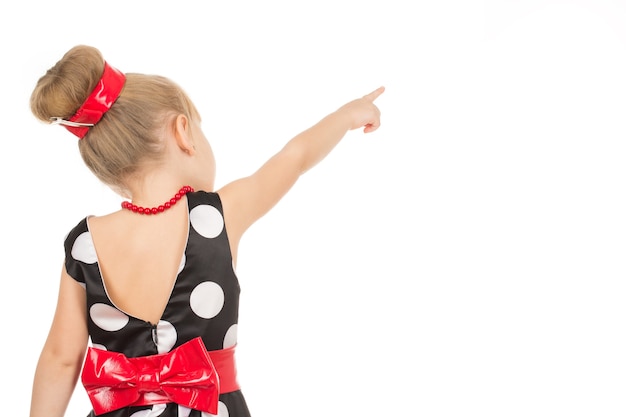 Aussehen! Kleines Mädchen, das gepunktetes Kleid trägt, das auf eine leere Stelle zeigt