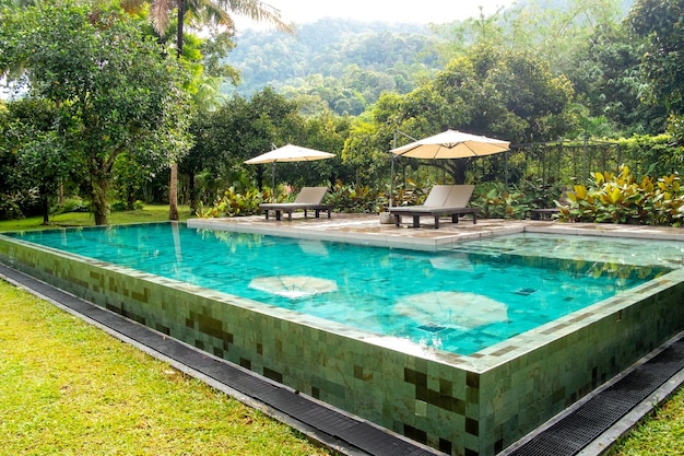 Außen Schwimmbad in einem Garten mit Rasen und Bäumen und Bergen im Hintergrund