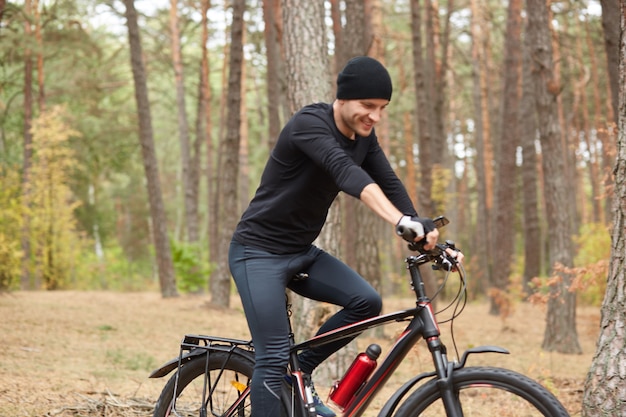 Außenaufnahme des jungen gutaussehenden Mannes, der Fahrrad auf Natur reitet