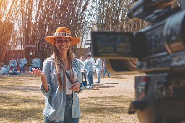 Foto außenbild einer jungen schönen frau, die ein glückliches, lächelndes, junges vlogger ist, das vor der kamera possiert.