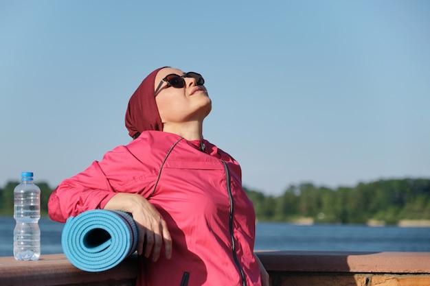 Außenporträt einer Altersfrau in Sportbekleidung mit Yogamatte