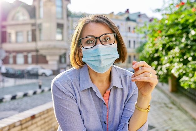 Außenporträt einer reifen Frau des Geschäfts in medizinischer Schutzmaske mit Brille. Geschäft, Pandemie, Epidemie, Gesundheitswesen und Medizin, gesunder Lebensstil