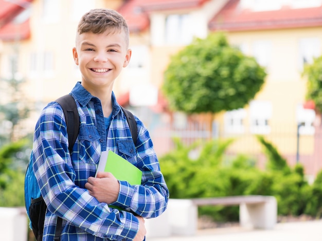 Foto außenporträt eines glücklichen teenagerkindes von 1214 jahren mit büchern und rucksack junger schüler beginn des unterrichts nach dem urlaub zurück zur schule konzept