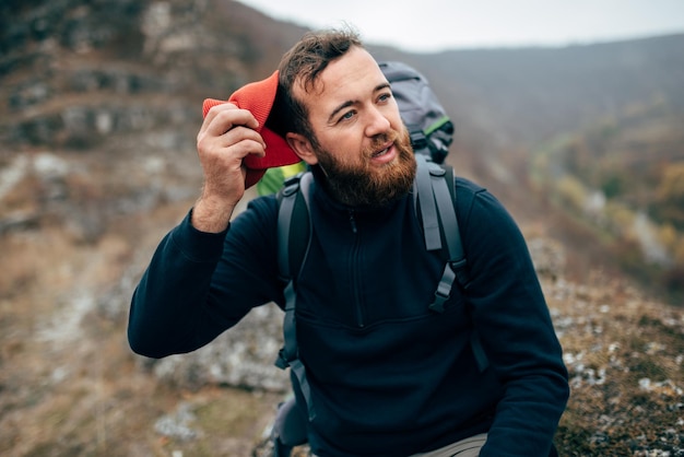 Außenporträt eines jungen Wanderers mit rotem Hut, der in den Bergen wandert