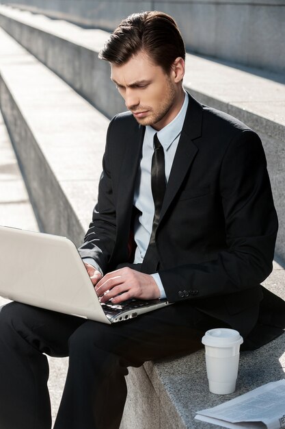 Außerhalb arbeiten. Abgeschnittenes Bild eines fröhlichen Geschäftsmannes mit Laptop