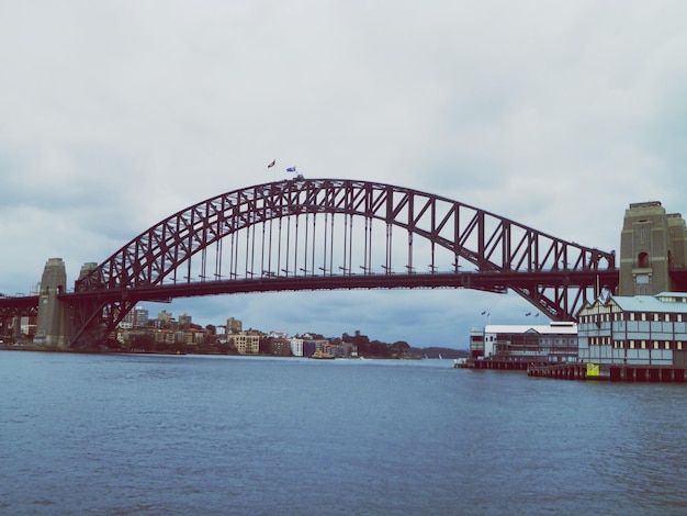 Foto aussicht auf die hafenbrücke über den fluss vor bewölktem himmel