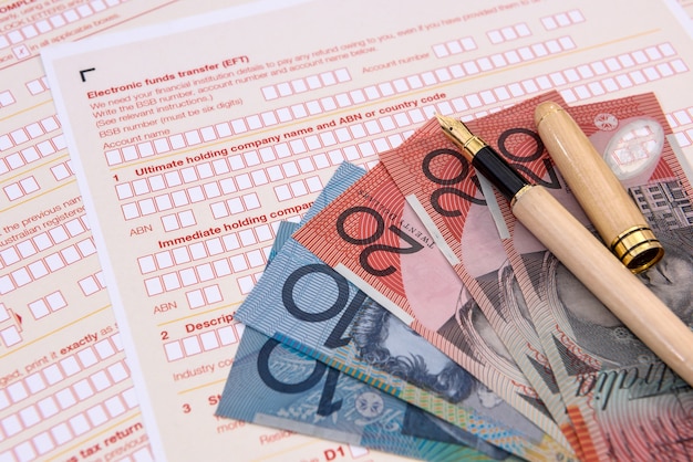 Australisches Steuerformular mit bunten australischen Dollarbanknoten schließen