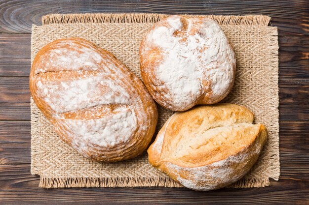 Auswahl an frisch gebackenem Brot mit Serviette auf rustikaler Tischplatte Ansicht Gesundes ungesäuertes Brot Französisches Brot