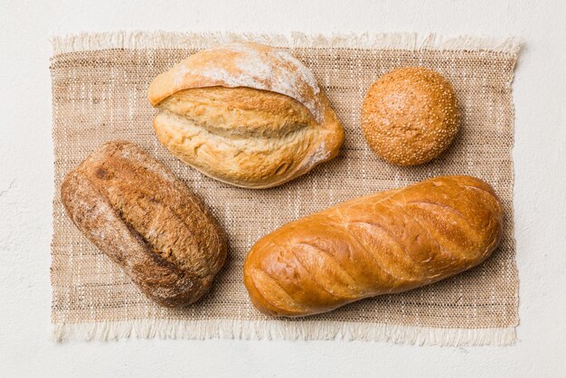 Auswahl an frisch gebackenem Brot mit Serviette auf rustikaler Tischplatte Ansicht Gesundes ungesäuertes Brot Französisches Brot