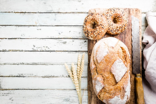 Auswahl an frisch gebackenem Brot und Brötchen auf Holztischhintergrund, Ansicht von oben