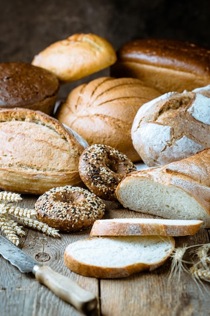 Auswahl an frisch gebackenem Brot und Brötchen auf Holztischhintergrund